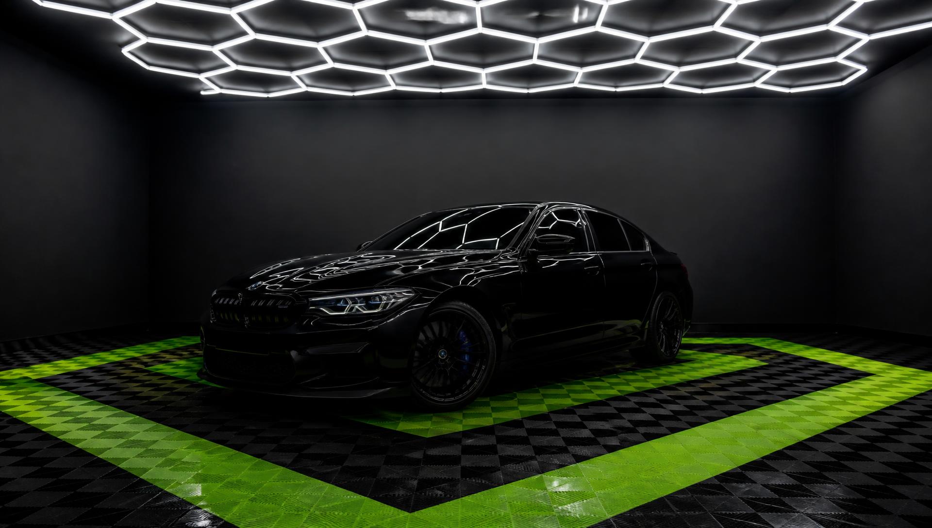 Carro premium preto em estúdio de detalhamento da Pequena Film's, com piso preto e verde e iluminação hexagonal